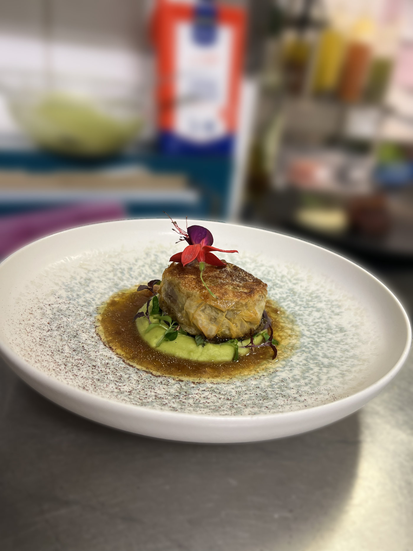 Pièce de viande dorée sur écrasé de légumes verts, jus relevé